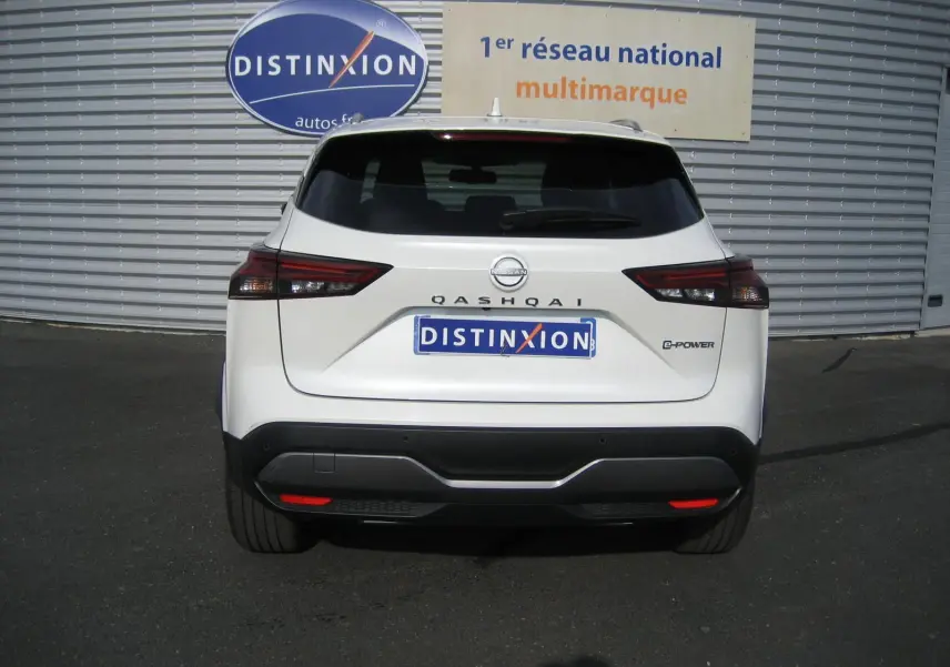 Vue arrière d'un Nissan Qashqai blanc 2024 avec badge E-POWER et plaque Distinxion visible sur un parking.