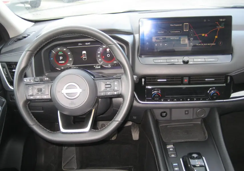 Vue intérieure du tableau de bord et volant du Nissan Qashqai blanc 2024 avec écran tactile et commandes au volant.