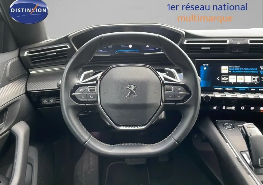 Vue intérieure centrée sur le volant cuir noir et le tableau de bord numérique de la Peugeot 508 2023.