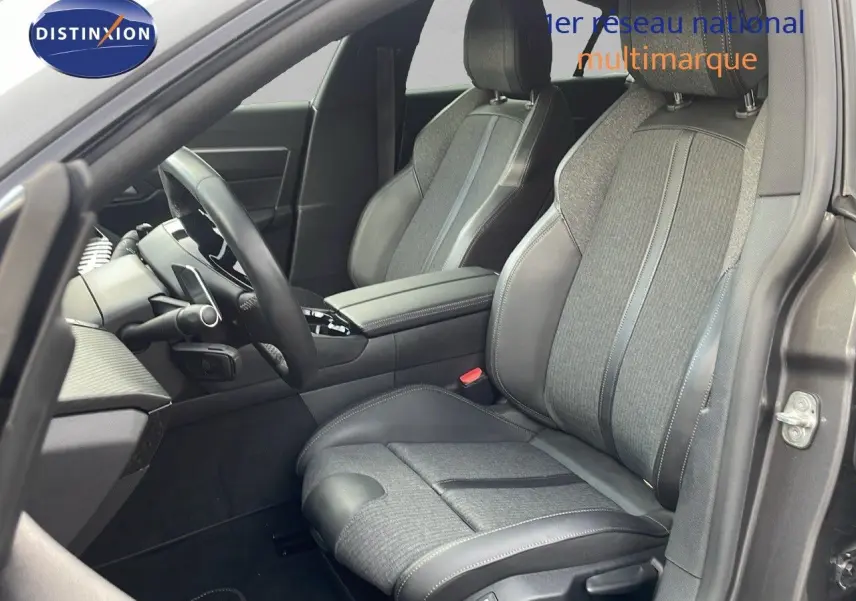 Vue intérieure côté conducteur de la Peugeot 508 gris platinium, sièges cuir et tissu noir avec console centrale visible.