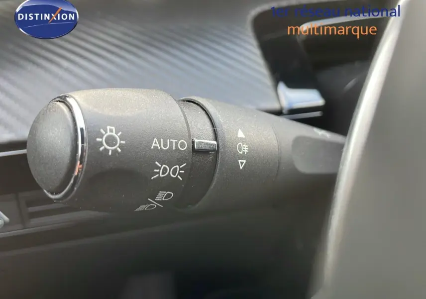 Gros plan sur la commande des phares automatique à gauche du volant dans une Peugeot 508 gris platinium 2023.