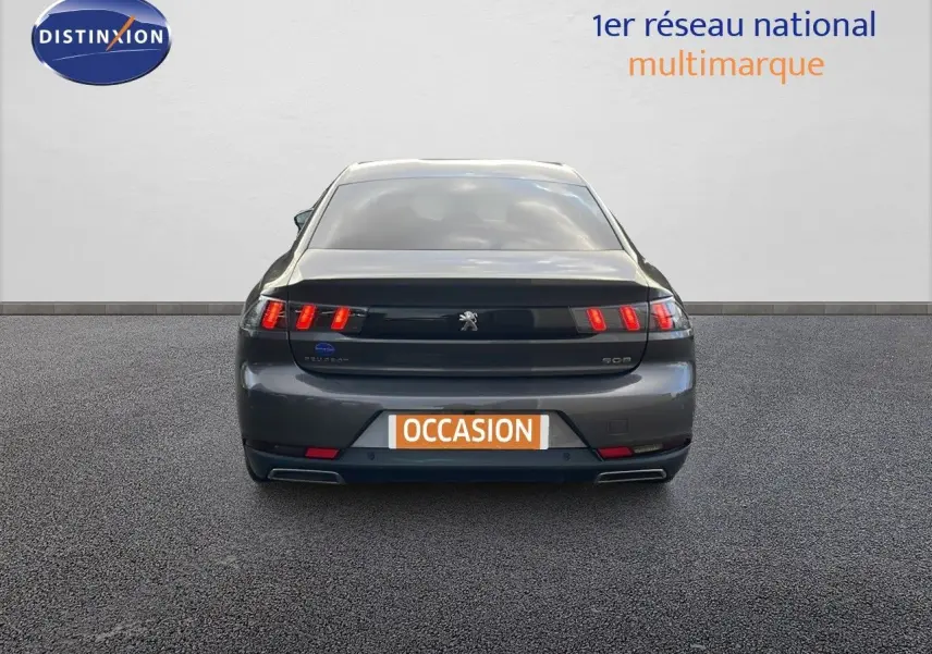 Vue arrière d'une Peugeot 508 gris platinium métal 2023 avec feux LED distinctifs et double sortie d'échappement.