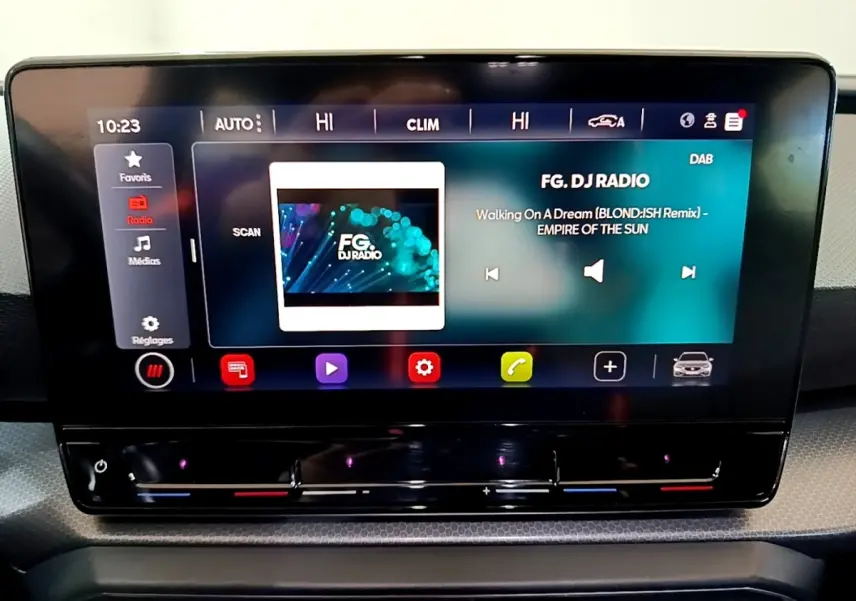 Écran tactile central allumé du tableau de bord du SEAT Leon gris clair, affichant la radio FG DJ Radio.