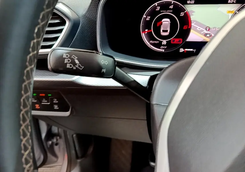 Vue rapprochée du commodo gauche et du tableau de bord numérique du SEAT Leon gris clair 2022, affichage 10,2 pouces.