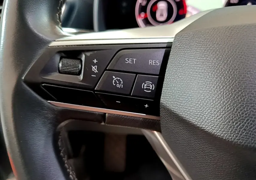 Gros plan sur les commandes du volant cuir de la SEAT LEON 2.0 TDI 150 DSG, avec régulateur de vitesse et aides à la conduite.
