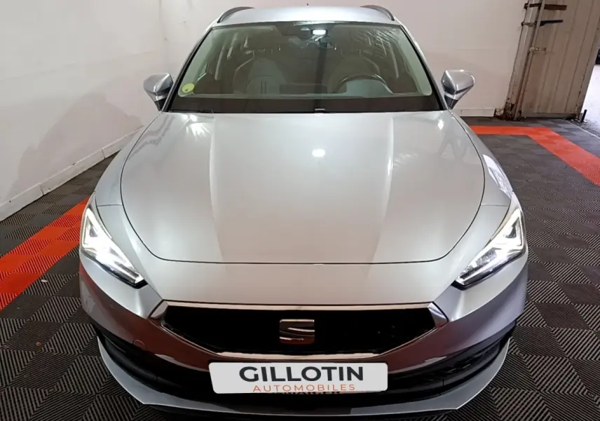 Vue frontale d'une SEAT LEON gris clair 2022 avec phares LED allumés dans un garage fermé.