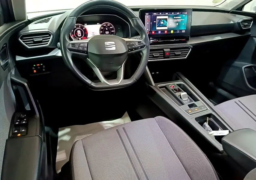 Intérieur avant de la SEAT Leon 2022, tableau de bord moderne avec écran tactile et volant multifonctions noir.