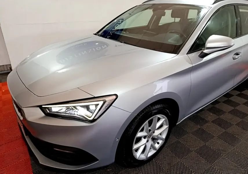 Vue 3/4 avant droit d'une SEAT LEON gris clair avec phares LED et jantes alliage visibles.