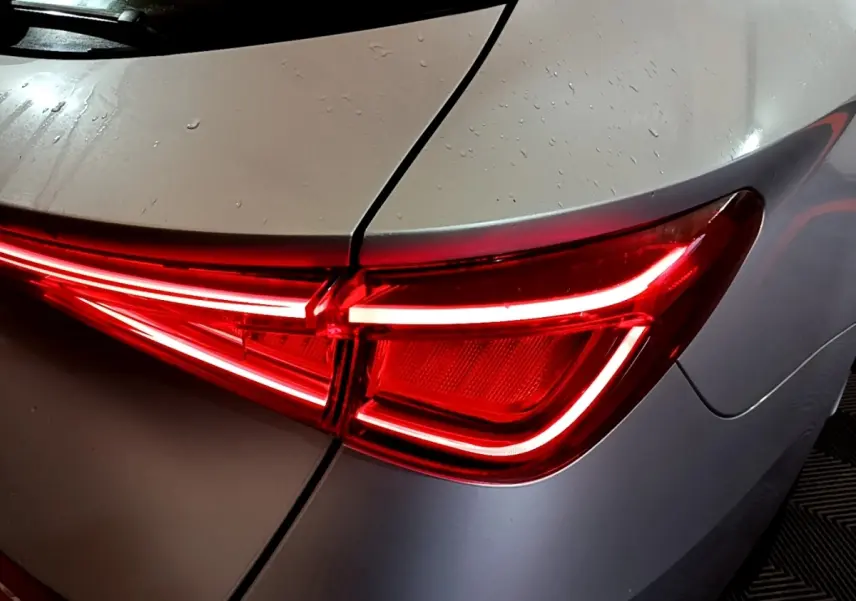 Gros plan sur le feu arrière droit rouge allumé d'une SEAT LEON gris clair 2022 sous pluie légère