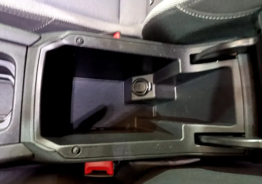 Vide-poche central noir avec prise 12V visible dans l'habitacle d'une SEAT LEON gris clair, vue de dessus rapprochée.