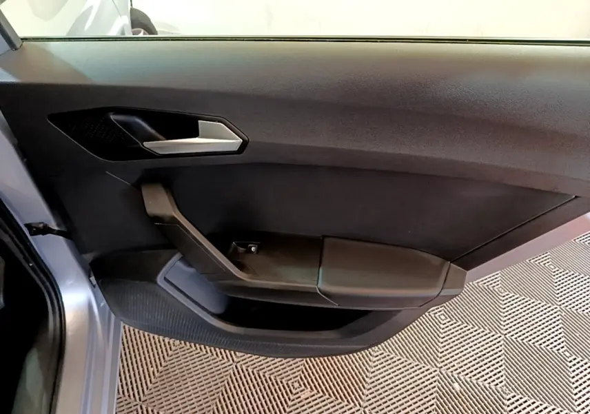 Porte intérieure côté gauche de la SEAT LEON gris clair 2022, avec poignée argentée et accoudoir noir.