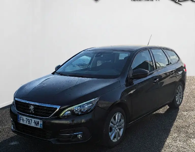 Peugeot 308 SW noire vue en 3/4 avant droit, avec jantes alu et calandre chromée visible.