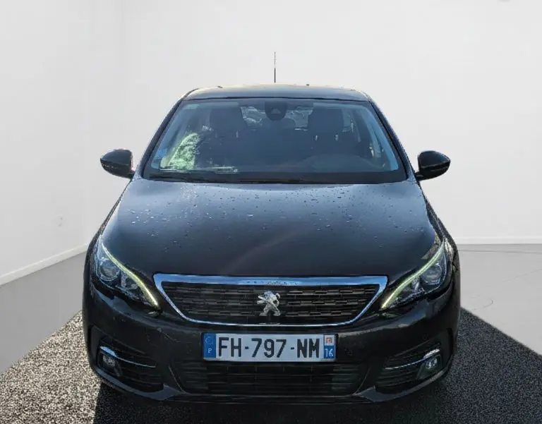 Vue avant d'une Peugeot 308 SW noire 2019 avec phares allumés et logo lion visible sur la calandre.
