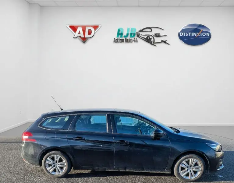 Peugeot 308 SW noire vue de profil côté gauche, avec jantes alliage et vitres arrière surteintées.
