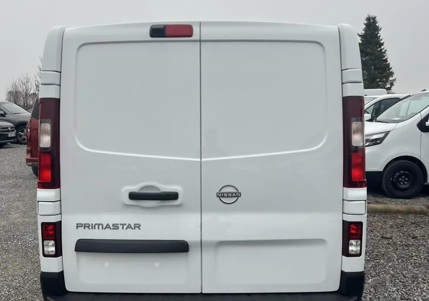 Vue latérale gauche d’un utilitaire Nissan Primastar blanc, version L2H1 avec porte latérale coulissante et jantes acier.