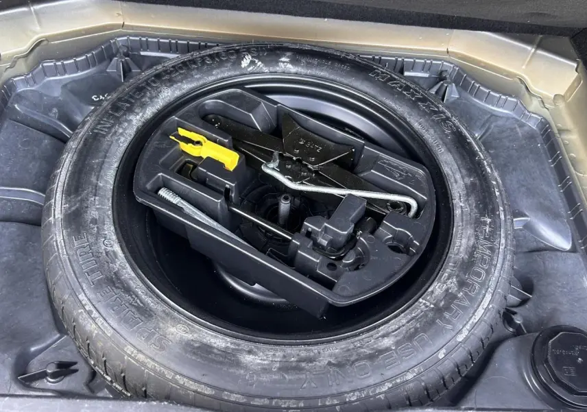 Gros plan sur la roue de secours galette et son kit d'outils dans le coffre d'un Citroën C4 Spacetourer gris Platinium.