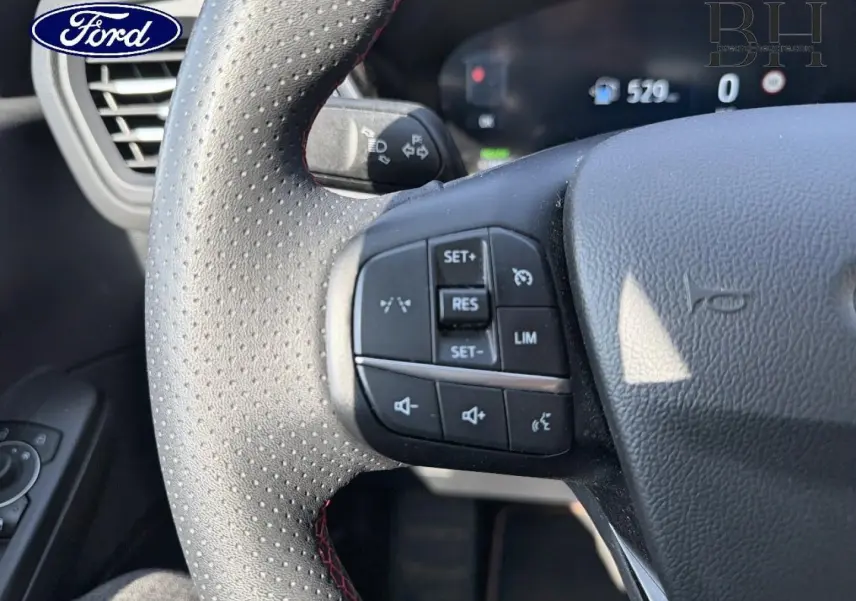 Gros plan sur le volant perforé avec commandes multifonctions du Ford Kuga 2025 noir Agate Métallisé.