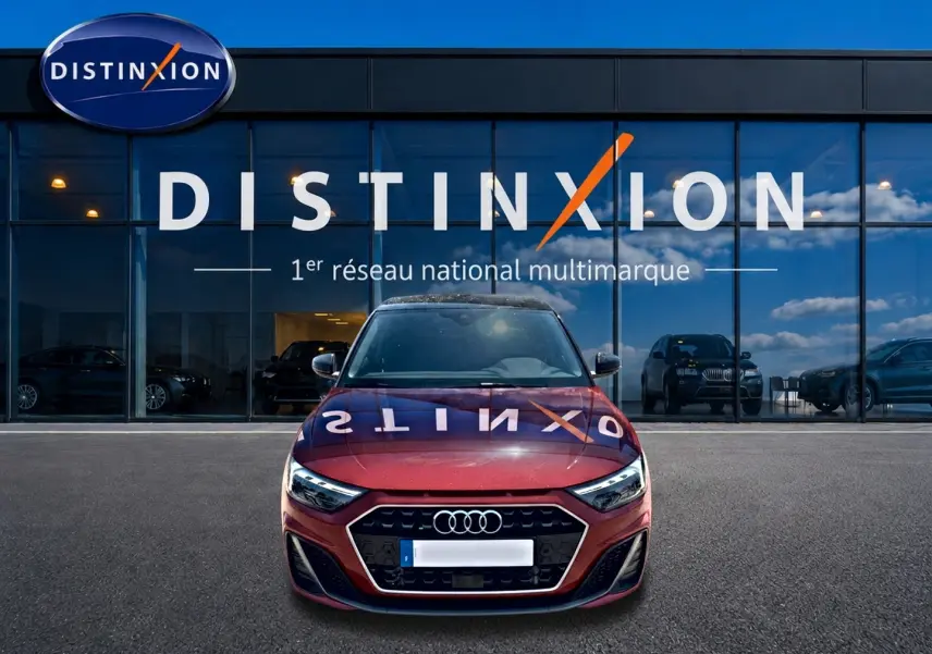 Audi A1 Sportback rouge et noir vue de face, avec calandre hexagonale et phares LED, devant une vitrine Distinxion.