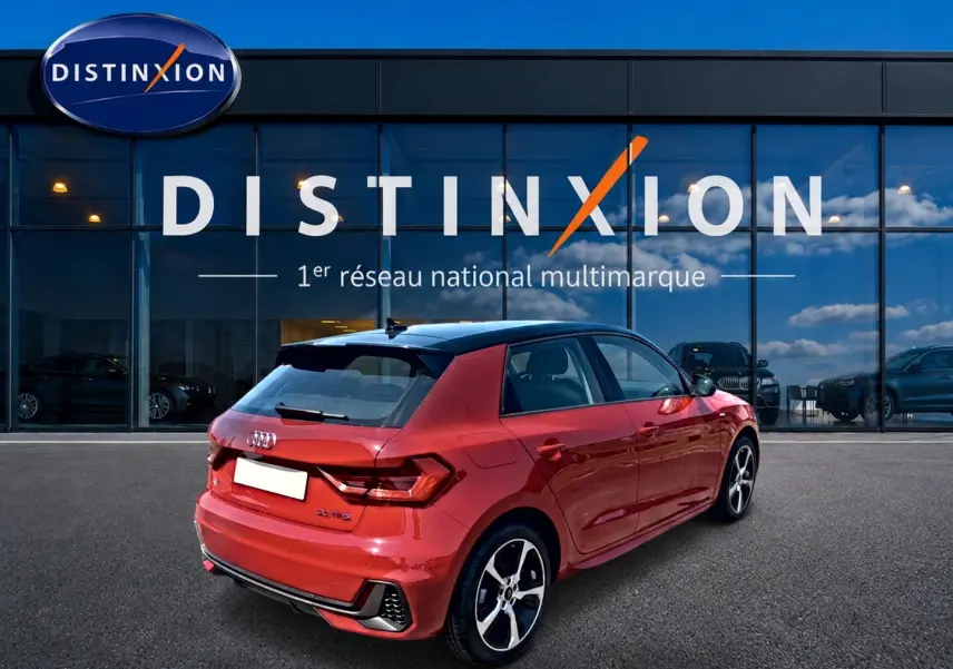 Audi A1 Sportback rouge et noir vue 3/4 arrière droit avec jantes alu et toit noir devant une vitrine Distinxion.