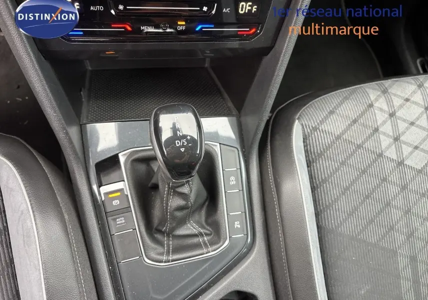 Vue rapprochée de la console centrale du Volkswagen Tiguan 2024 en Reflex Silver, avec levier de boîte auto et sièges tissu cuir.