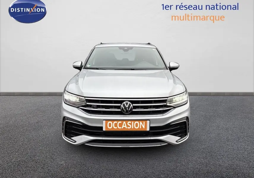 Vue frontale d'un Volkswagen Tiguan 1.5 TSI R-Line 2024 en Reflex Silver Metal avec calandre et phares LED allumés.