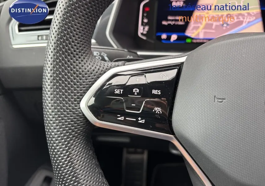 Gros plan sur le volant multifonction en cuir perforé d’un Volkswagen Tiguan 2024 Reflex Silver, avec commandes de régulateur.