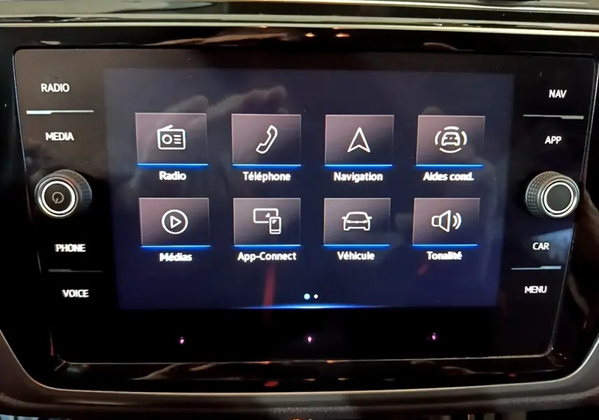 Écran tactile central du Volkswagen Touran 2023 affichant les menus radio, téléphone, navigation et aides à la conduite.