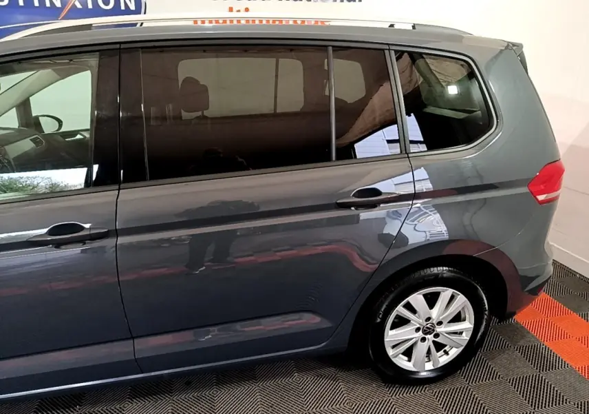 Profil côté droit du Volkswagen Touran gris foncé 2023 avec jante aluminium et vitres teintées.