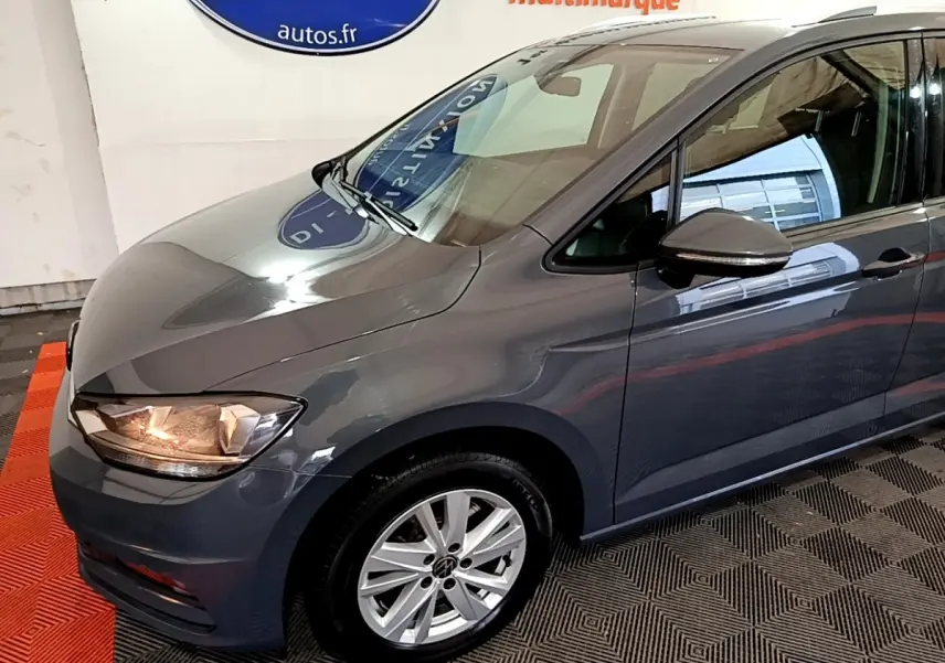 Vue 3/4 avant gauche d'un Volkswagen Touran gris foncé avec jantes alliage et rétroviseur assorti.