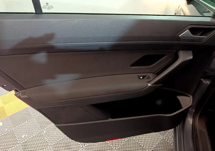 Intérieur côté gauche de la porte avant gris foncé du Volkswagen Touran 2023 avec poignée et commande de vitre.