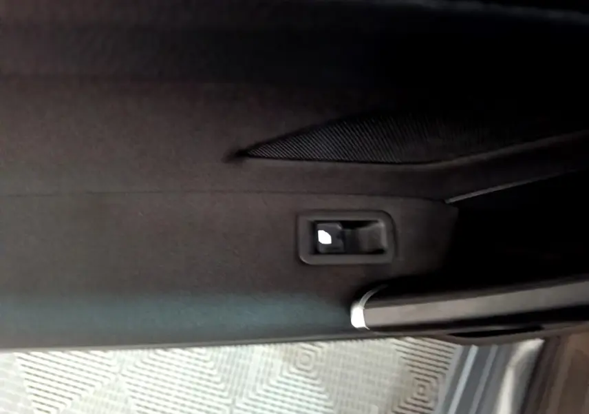 Poignée intérieure de porte arrière droite du Volkswagen Touran gris foncé 2023 avec habillage tissu noir.