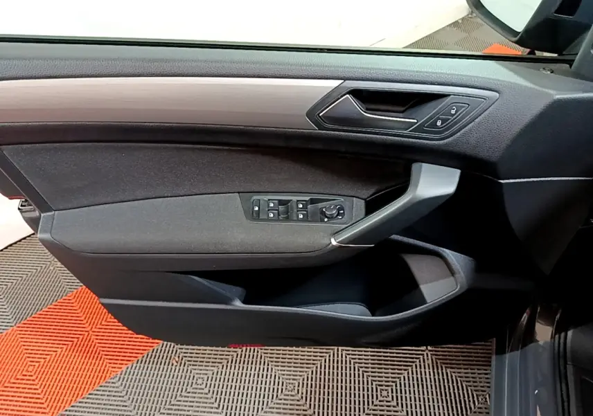 Vue intérieure côté gauche de la porte conducteur du Volkswagen Touran gris foncé avec commandes de vitres et verrouillage.