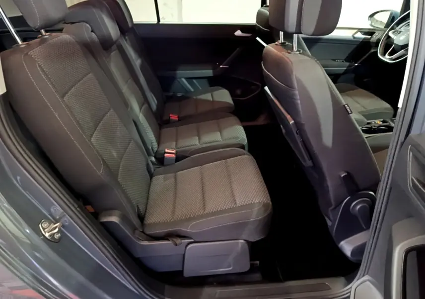 Vue intérieure côté gauche sur les sièges arrière noirs du Volkswagen Touran gris foncé 2023, avec détails tissu et appuie-têtes.