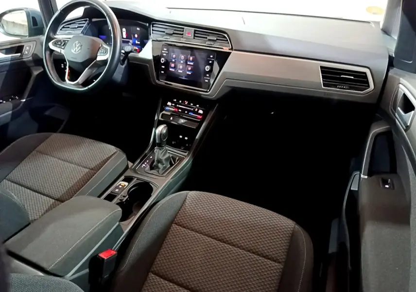 Intérieur avant du Volkswagen Touran 2023 gris foncé, vue côté conducteur avec tableau de bord digital et écran tactile central.