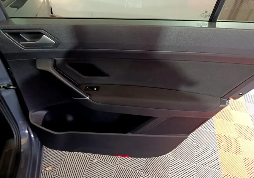 Porte arrière gauche ouverte du Volkswagen Touran gris foncé 2023, intérieur noir avec poignée et rangement visible.