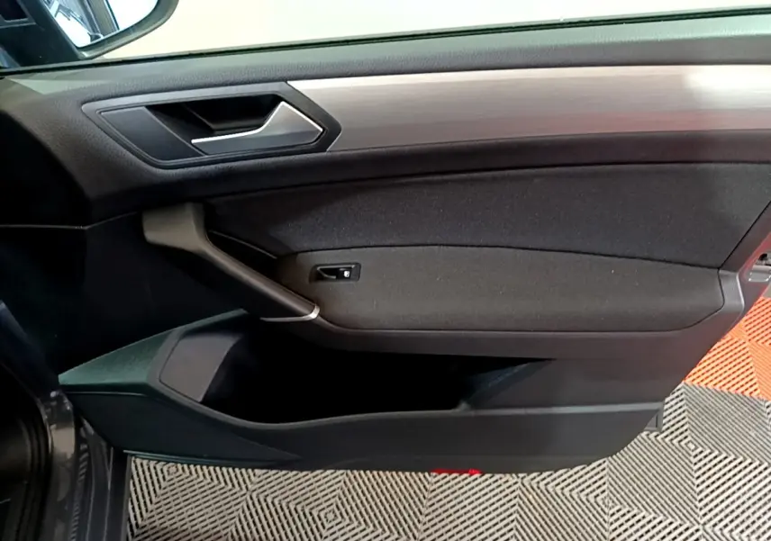 Porte intérieure côté gauche du Volkswagen Touran gris foncé 2023, avec poignée argentée et garniture noire.
