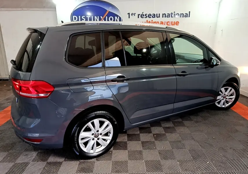 Vue latérale droite d'un Volkswagen Touran gris foncé 2023 avec jantes alliage et vitres teintées.