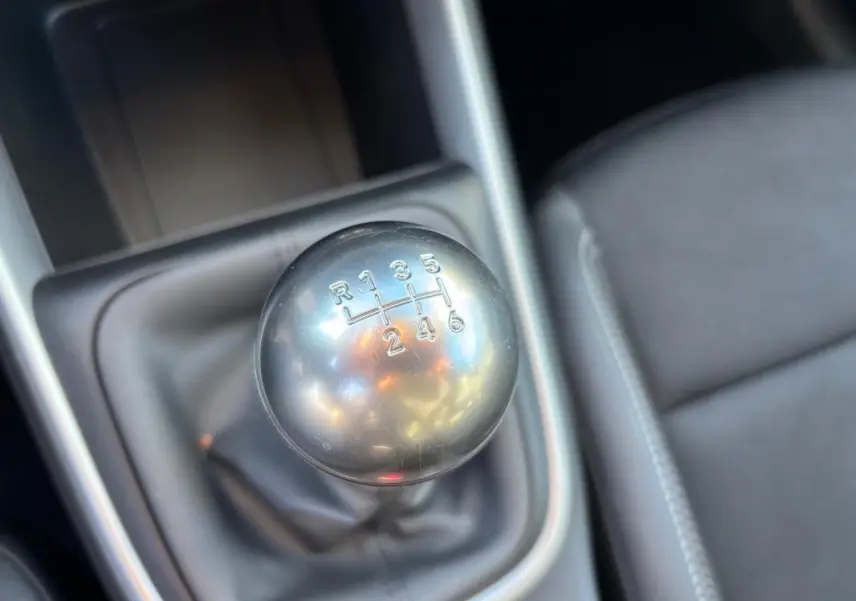 Gros plan sur le levier de vitesses manuel argenté du Jeep Avenger noir, avec siège conducteur en tissu gris visible à droite.