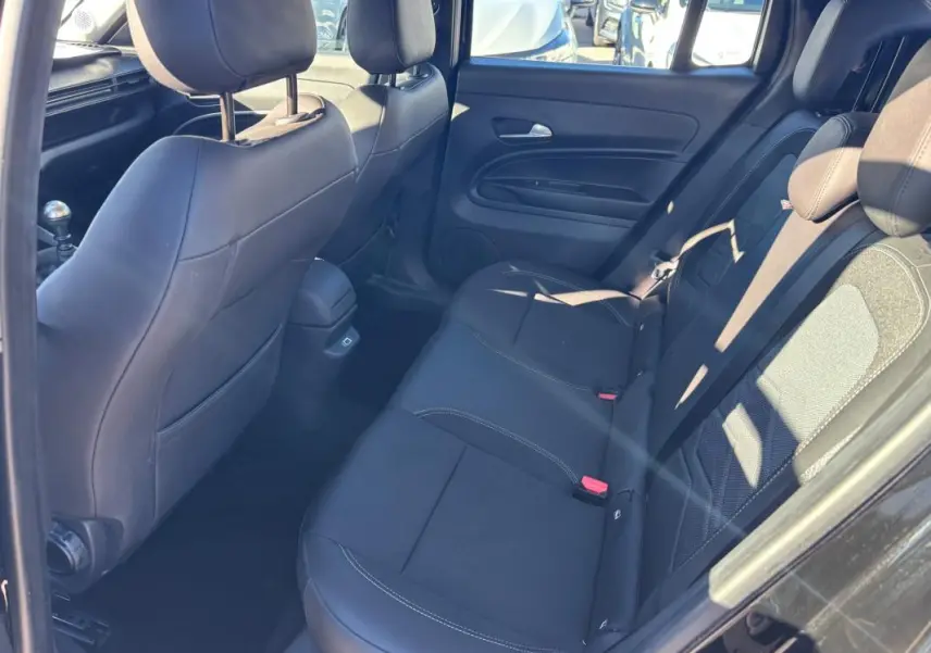 Vue intérieure arrière côté droit du Jeep Avenger noir 2024, montrant les sièges en tissu et cuir avec appuie-têtes.