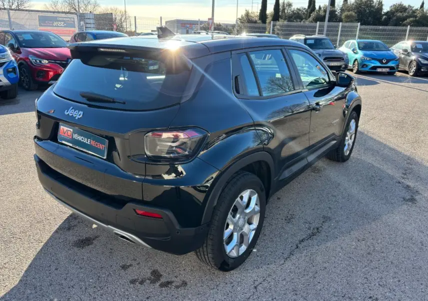 Vue 3/4 arrière droite d'un Jeep Avenger noir 2024 avec jantes alliage et feux arrière LED dans un parking.