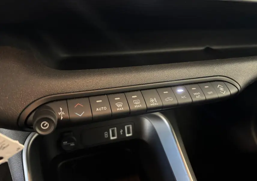 Vue intérieure du tableau de bord du Jeep Avenger noir 2024, montrant les commandes de climatisation et les ports USB.