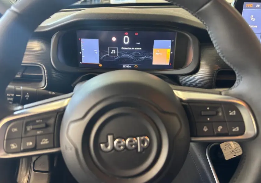 Vue rapprochée du tableau de bord et volant noir du Jeep Avenger 2024 avec affichage numérique et commandes intégrées.