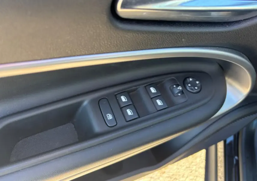 Détail des commandes des vitres électriques et rétroviseurs sur la porte côté conducteur d’un Jeep Avenger noir 2024.