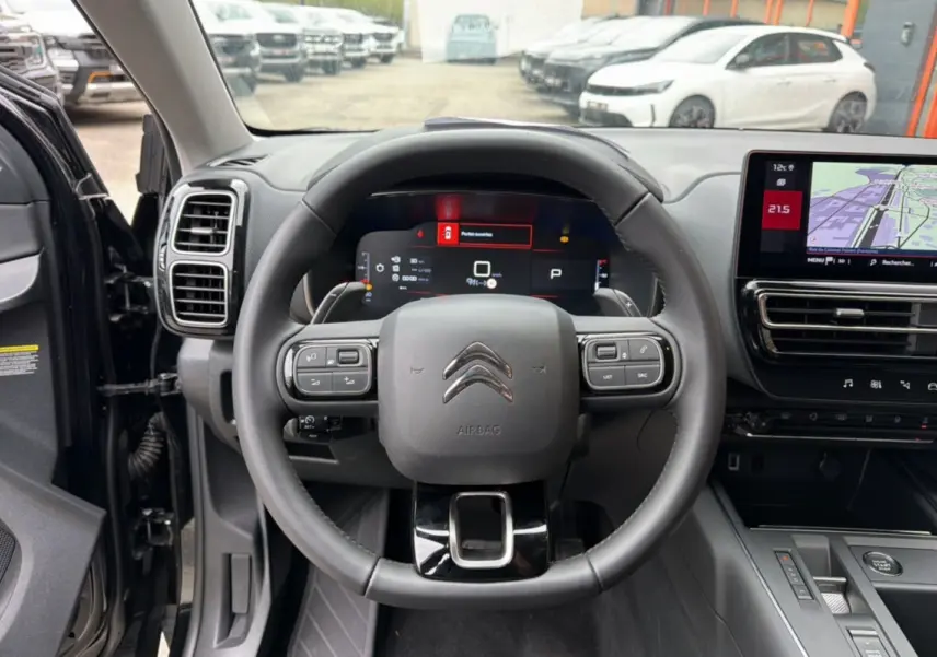 Vue intérieure centrée sur le volant cuir noir et le tableau de bord digital d'une Citroën C5 Aircross 2025.