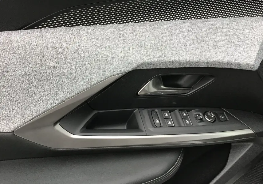 Détail de la porte côté conducteur du Peugeot 3008 2026, avec tissu gris clair et commandes électriques intégrées.