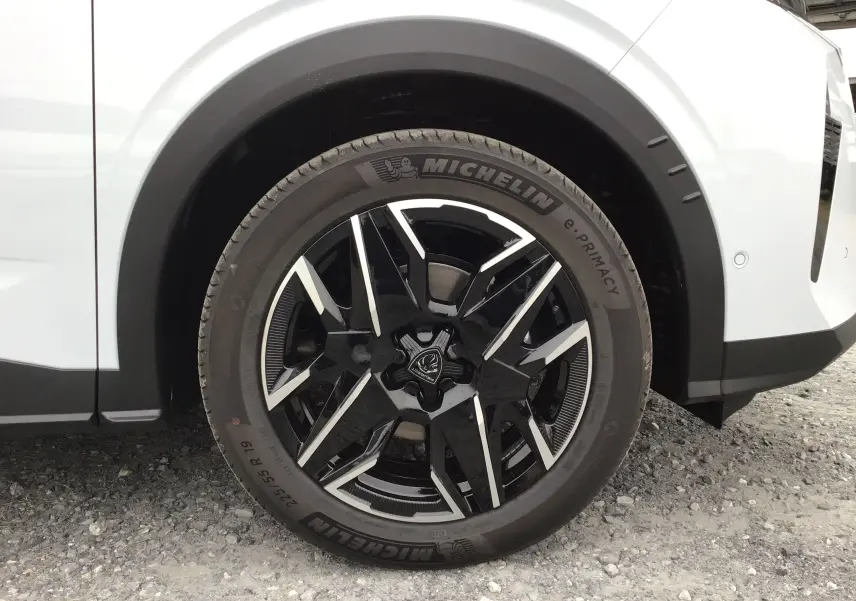 Gros plan sur la roue avant droite du Peugeot 3008 blanc Okenite, jante alliage noire et argentée, pneu Michelin.