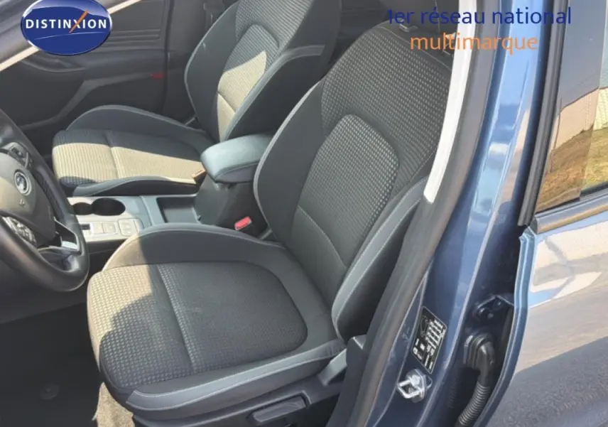 Vue intérieure côté conducteur de la Ford Focus SW bleu foncé, montrant les sièges avant et l'accoudoir central.
