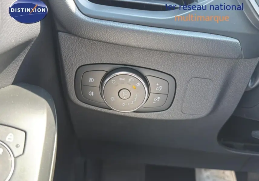 Gros plan sur la commande d’éclairage à gauche du volant dans l’habitacle sombre d’une Ford Focus SW bleu foncé 2022.