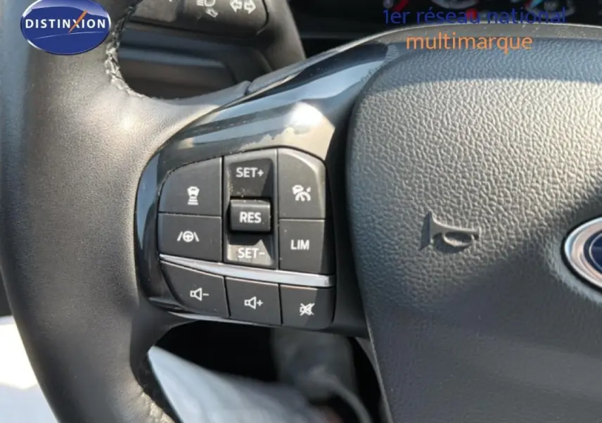 Gros plan sur le volant noir de la Ford Focus SW 2022, montrant les commandes du régulateur de vitesse et volume sonore.