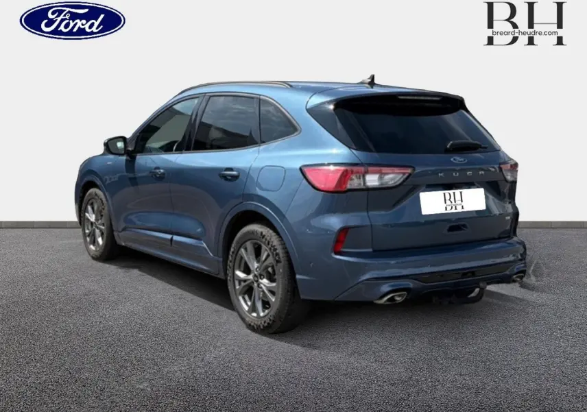 Ford Kuga bleu Abysse en 3/4 arrière droit, avec vitres surteintées et double sortie d’échappement visible.